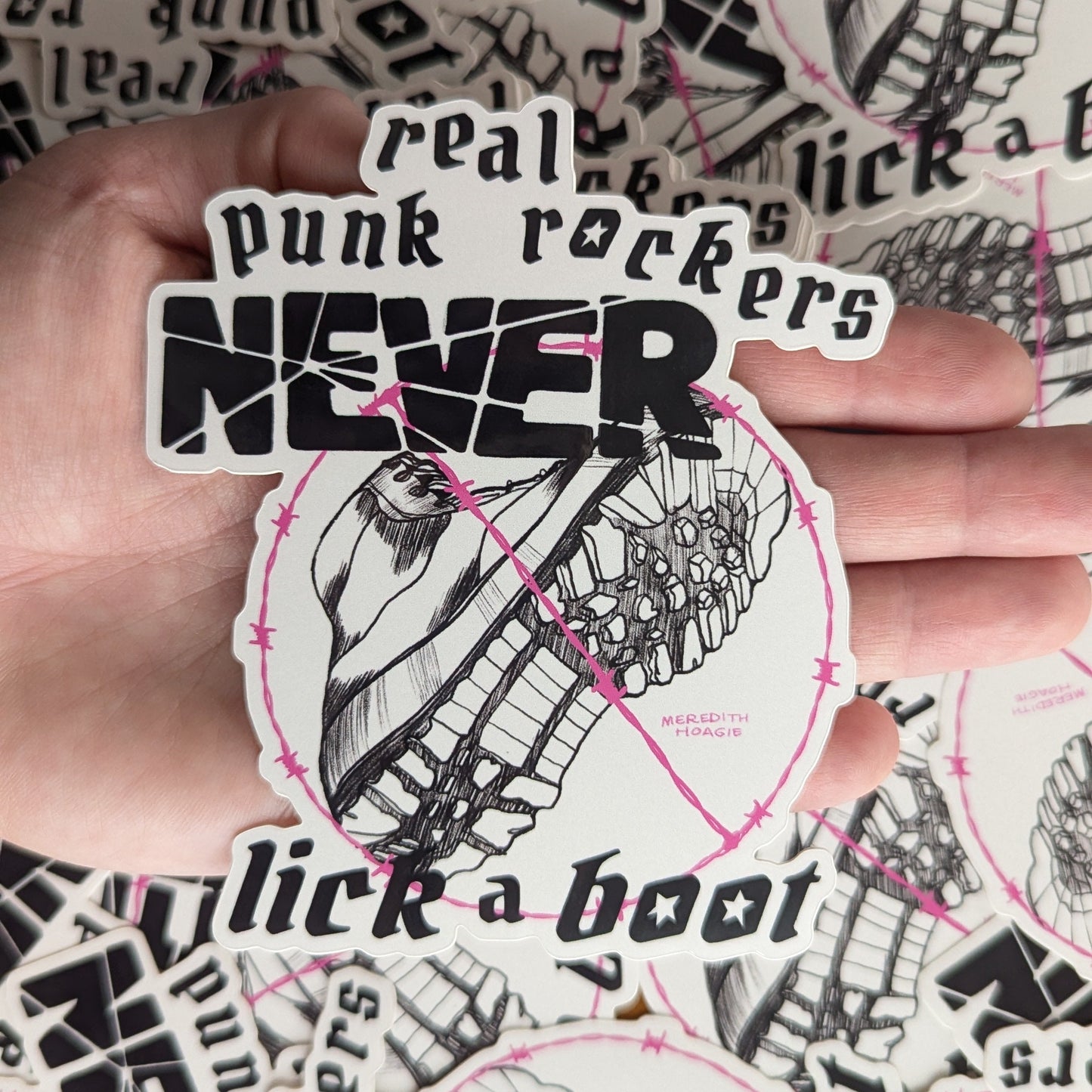 Sticker with text 'real punk rockers NEVER lick a boot' held by a hand against a background of similar stickers.