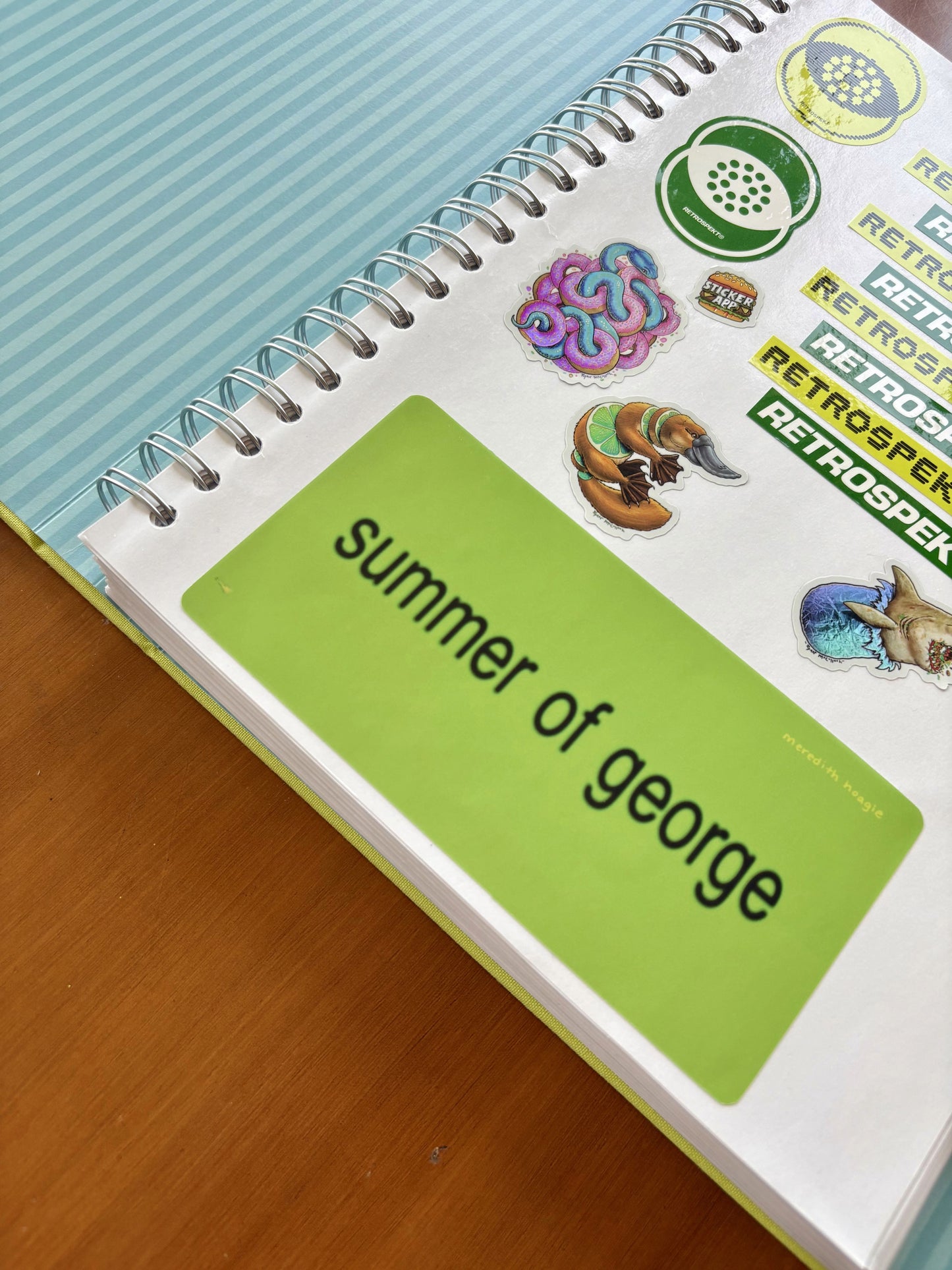 A green sticker reading 'summer of george' on The Coffee Table Sticker Book with other stickers by Meredith Hoagie and various artists.