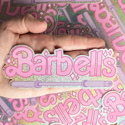 Pink holographic 'Barbells' sticker by Meredith Hoagie held over a background of similar stickers.