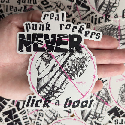 Sticker with text 'real punk rockers NEVER lick a boot' held by a hand against a background of similar stickers.