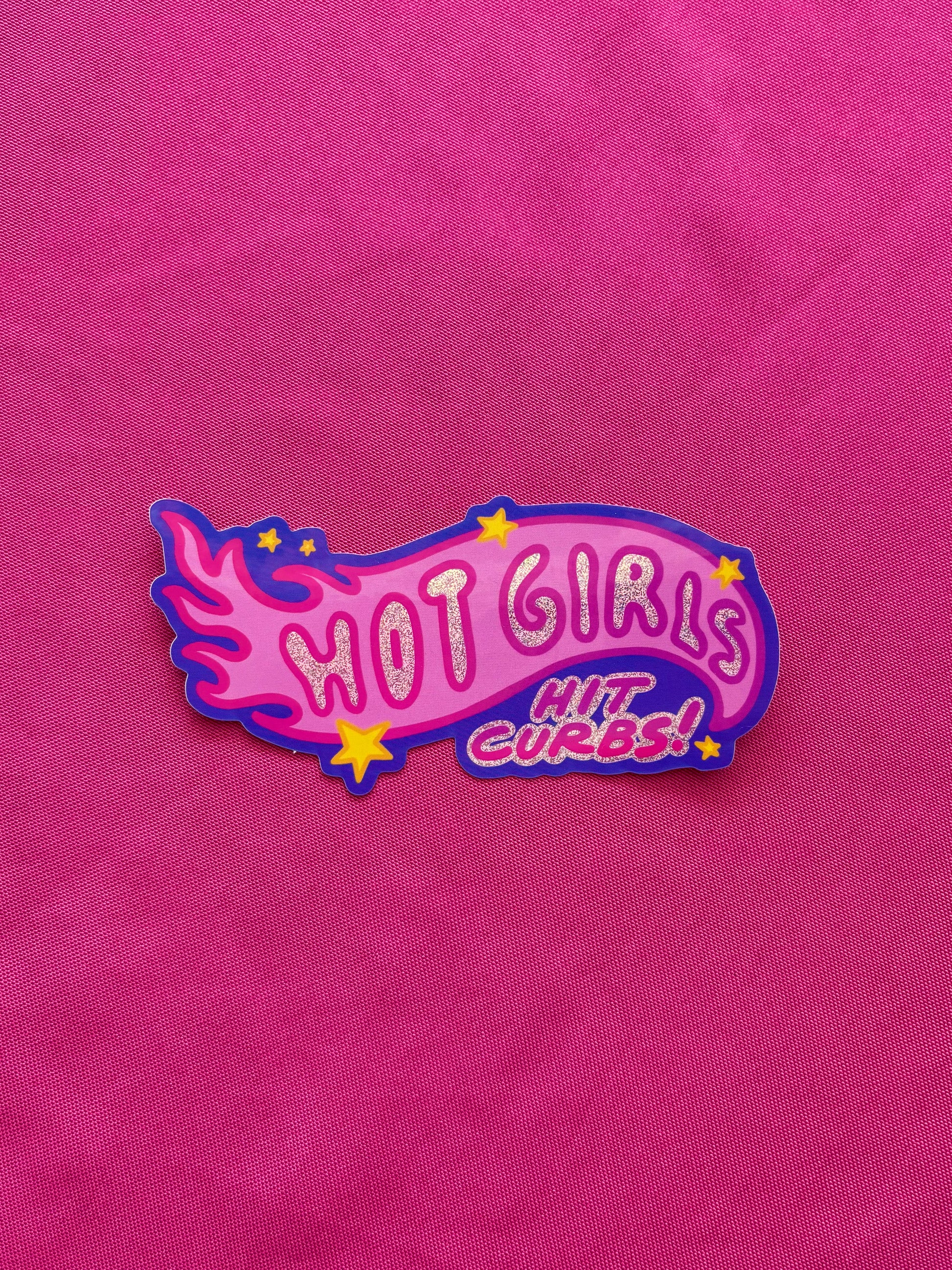 Pink die cut sticker with 'HOT GIRLS HIT CURBS!' text on a pink tablecloth