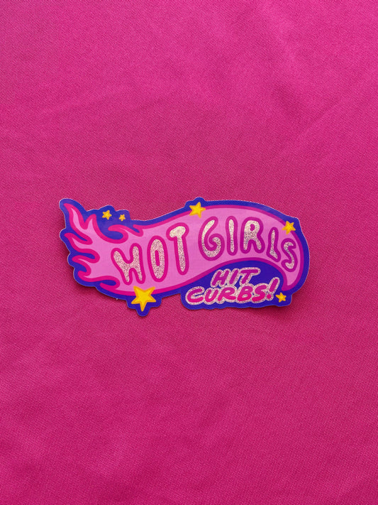 Pink die cut sticker with 'HOT GIRLS HIT CURBS!' text on a pink tablecloth