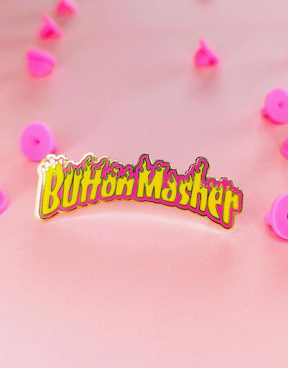 button masher gaming enamel pin on pink background